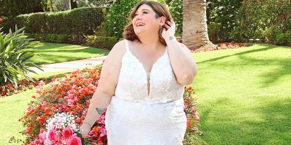 Bride wearing a plus size wedding dress while holding flowers in a garden